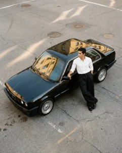 AWAISHU black wide-leg trousers, model leaning on a black BMW